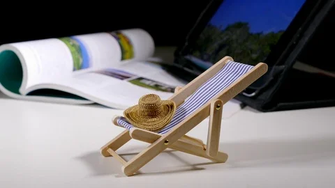 Model deckchair and hat in front of holiday brochure. Stock-Footage 75952931