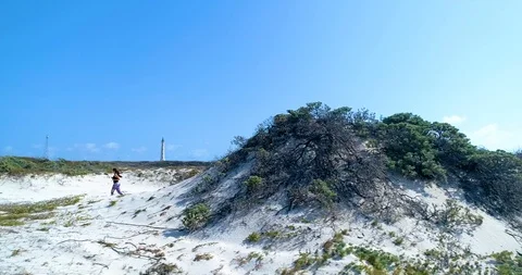 Model exercising running up the dunes near lighthouse Stock-Footage 104574517