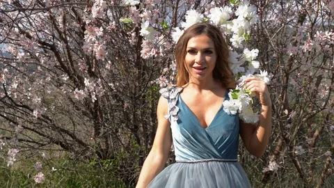 Model in a fancy dress posing with a blooming almond tree Stock Footage 125763735