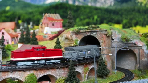 Model freight train exits the tunnel and passes over a bridge Stock-Footage 260808824