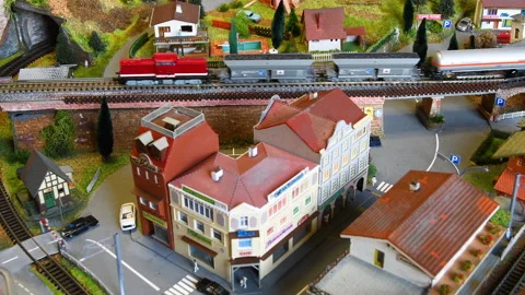 Model freight train passes on a bridge near a city. Video stock 260807050