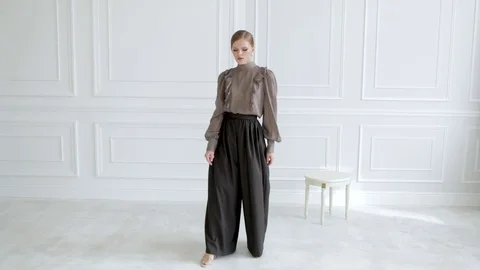 Model Girl in a brown blouse posing on a white background in the interior Stock Footage 123572566