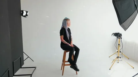 Model girl with dreadlocks and a tattoo is sitting in a white studio Stock Footage 183923053