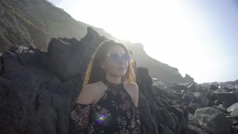 A model with glasses poses on a large stone Stock Footage 219349987