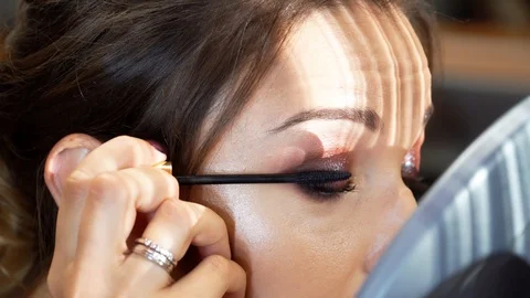 A model with hairstyle and make-up draws herself eyelashes with a black mascara 動画素材 127501918