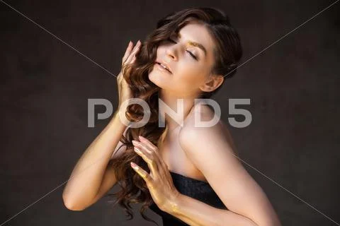Model With Hands In Gold Tint Touching Beautiful Wavy Hair