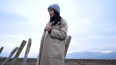 Model in hat and long coat poses in wasteland slow motion Stock Footage 105293872