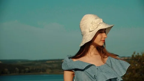 Model in hat on the background of a river and greenery looking into the distance Stock Footage 95405250