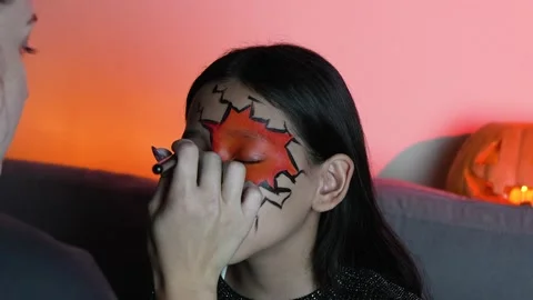 A model is having her face painted with a spooky design for Halloween Stock Footage 319825736