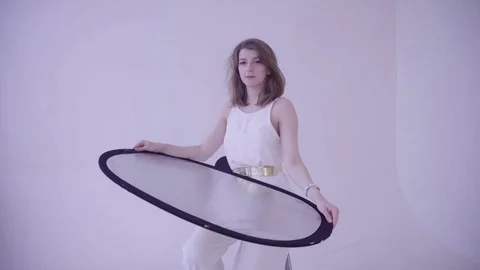 The model holds a light reflector on a photo shoot in the studio Stock Footage 77004902