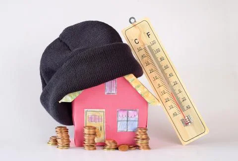 Model home with winter hat, stacks of money and thermometer.Rising heating .. Stock Photos