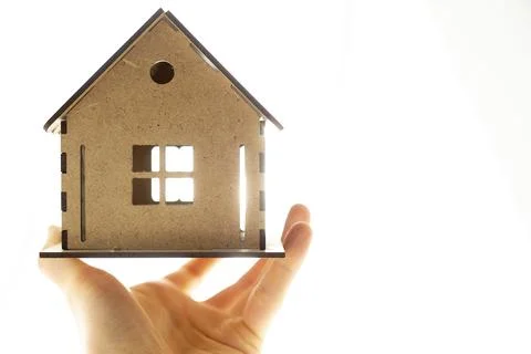 A model house on the background of the sun in the hand of a real estate agent. Stock Photos