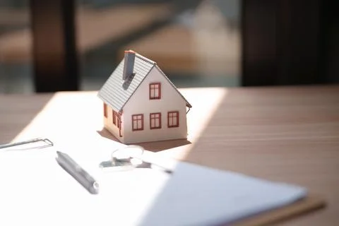 Model House on Desk with Documents and Pen Representing Real Estate Transacti Stockfoto's