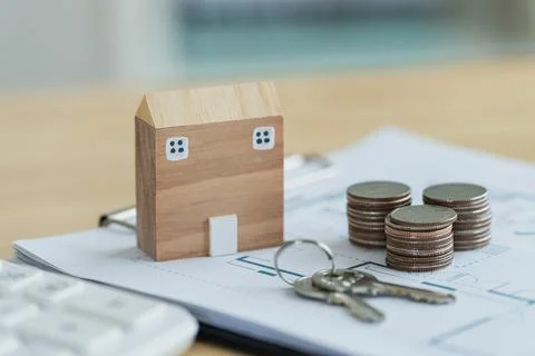 Model house on financial documents with keys and coins representing real es.. Stock Photos