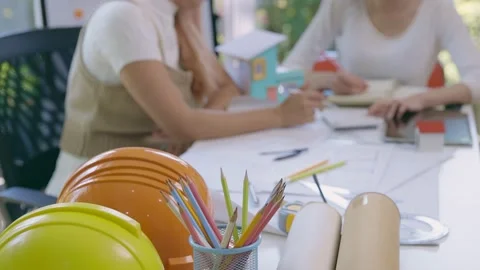 Model house with helmets and two female architects discussing work issues. Stock Footage 235539308