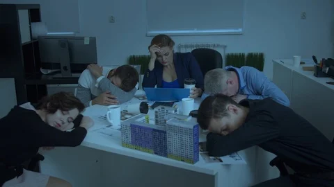 Model of house on table, workmates sit and sleep, woman try to work Stock Footage 121800348