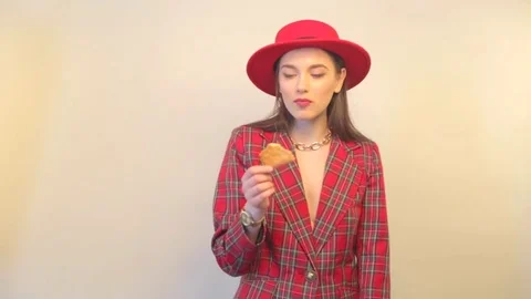 Model in jacket and hat eats cookies and smiles during shooting time in studio Stock Footage 73370364