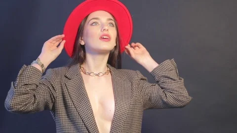 Model in jacket touches red hat and posing near the wall Stock Footage 73366088