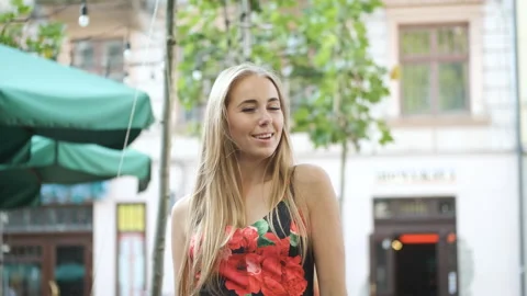 A model with long legs in a red and black dress walks around a European city and Stock Footage 138887693