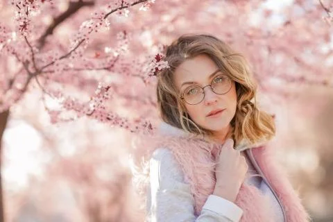 A Model looking at camera, posing in street, near blooming flowers. Female Stock Photos
