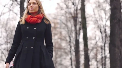 Model looking girl goes to camera in black coat along the alley in the park Stock Footage 82502021