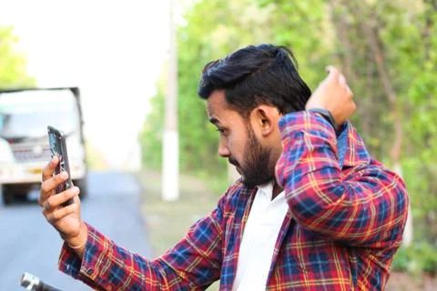 Model looking at his mobile and shorting his shirt Stock Photos