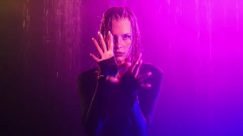 The model looks at the camera and splashes her hands at the camera. Stock Footage 282154327