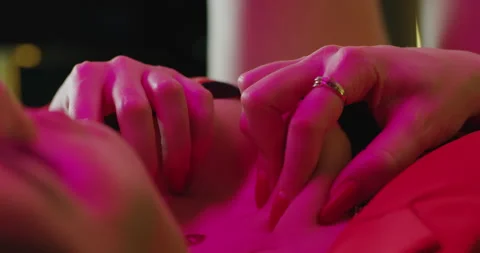 The model is lying on the bed in the evening in red clothes. Beautiful young  Stock Footage 161306874