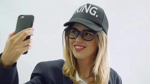 Model makes selfie with smartphone, looks at camera and smiles Stock Footage 99782404