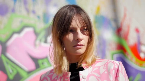 Model with pink dress posing in front of graffiti and smiling Stock Footage 59736661