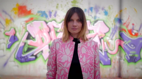 Model with pink dress posing in front of graffiti looking in camera and smiling Видео 59736808