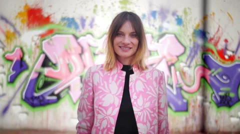 Model with pink dress posing in front of graffiti and smiling Video stock 59736938