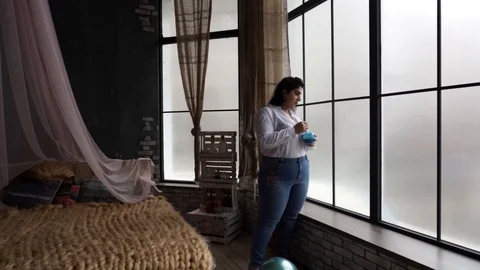 Model plus size drinks juice near the window Stock Footage 106062990