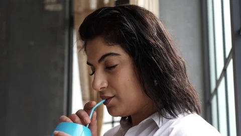 Model plus size drinks juice near the window Stock Footage 106064202