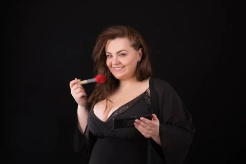 Model plus size. happy smiling girl posing with cosmetic, doing makeup for he Stock Photos