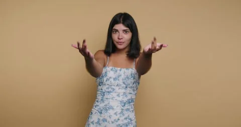 Model poses against a plain background and smiles with arms open, inviting .. Stock-Footage 326792980