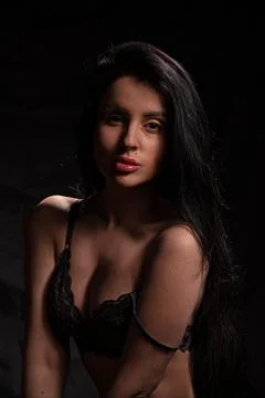 Model poses in dark setting wearing delicate lingerie with long hair cascading Stock Photos
