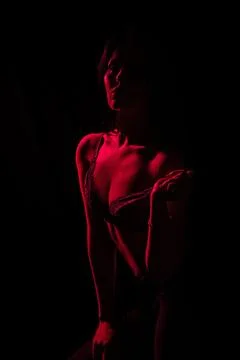 Model poses dramatically with red lighting creating a striking silhouette Stock Photos
