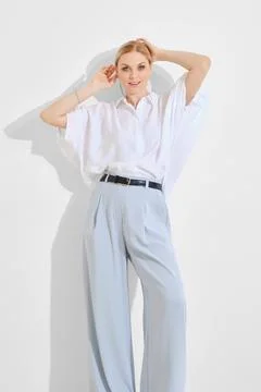Model poses elegantly in light clothing against a minimalist backdrop durin.. Stock Photos