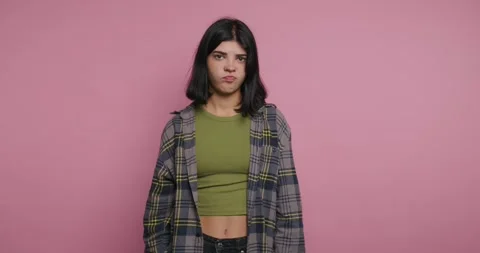 Model poses in front of pink wall wearing shirt and plaid jacket while maki.. Vídeos de archivo 326792400