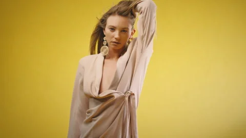 Model posing and touching hair looking straight at camera yellow background Stock Footage 275628045