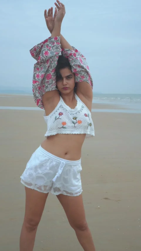 Model Posing Confidently on a Cloudy Beach Day in Stylish Summer Attire Stock Footage 323050783