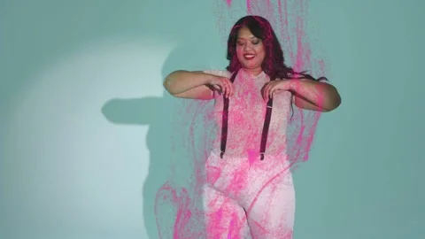 Model posing holding straps in teal set, magenta paint descending covering Stock Footage 333034897
