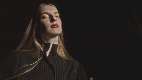 Model posing with sunlight illuminating face at night Video stock 289896541