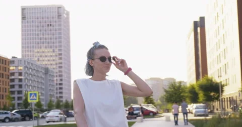 Model Posing. Town. Street of New District. Girl Hand Raises Sunglasses. Smiles Stock Footage 136724730