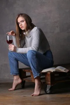 Model in pullover holding wineglass. Gray background Stock Photos
