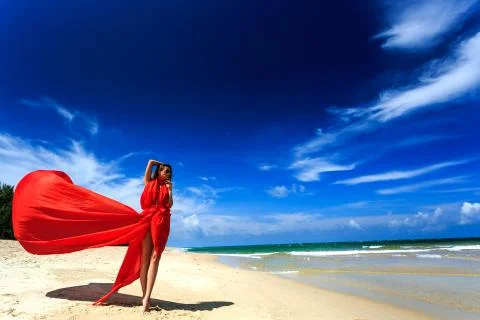 Model in red dress posing on beach Stock Photos