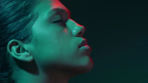 Model in red &amp; teal light sprays fragrance profile sitting Stock-Footage 343057918