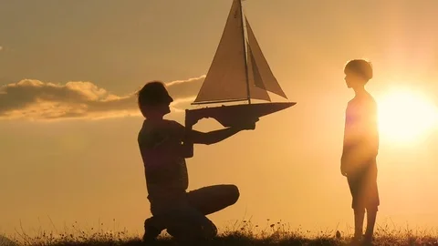 A model of a sailboat. A man is holding a ship model against the sky.  Stock Footage 79106544