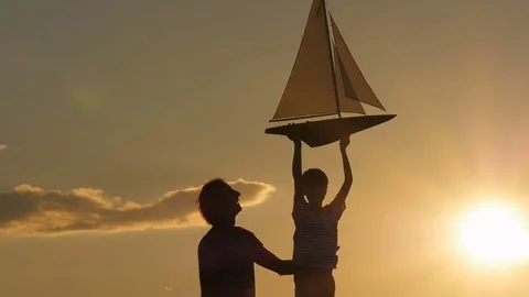A model of a sailboat. A man is holding a ship model against the sky.  Stock Footage 79106673